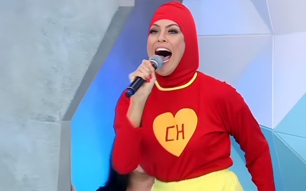Renata Fan está vestida como Chapolin Colorado e abre a boca bem feliz no cenário do Jogo Aberto
