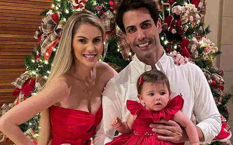Bárbara Evans, o marido Gustavo Theodoro e a filha Ayla no colo em frente a uma árvore de Natal