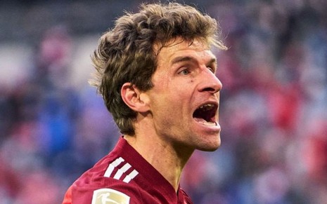 Thomas Müller, do Bayern, veste uniforme vermelho com detalhes brancos e grita ao comemorar gol