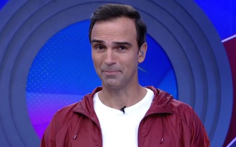 Tadeu Schmidt usa blusa vermelha e camiseta branca no estúdio do BBB 22, da Globo