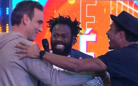 Tadeu Schmidt, Douglas Silva e Paulo André se abraçando na final do BBB 22, da Globo