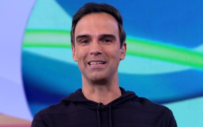 Tadeu Schmidt com uma camisa preta no estúdio do BBB 22, sorrindo na apresentação do programa