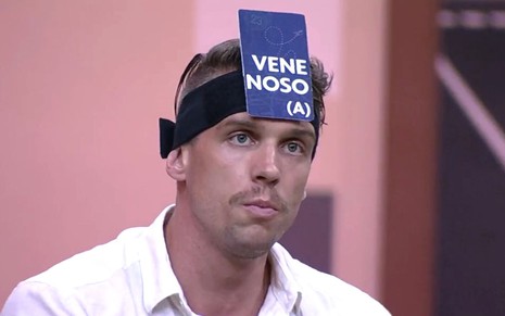 Cristian Vanelli com uma placa de venenosa colada na cabeça no Jogo da Discórdia do BBB 23, da Globo