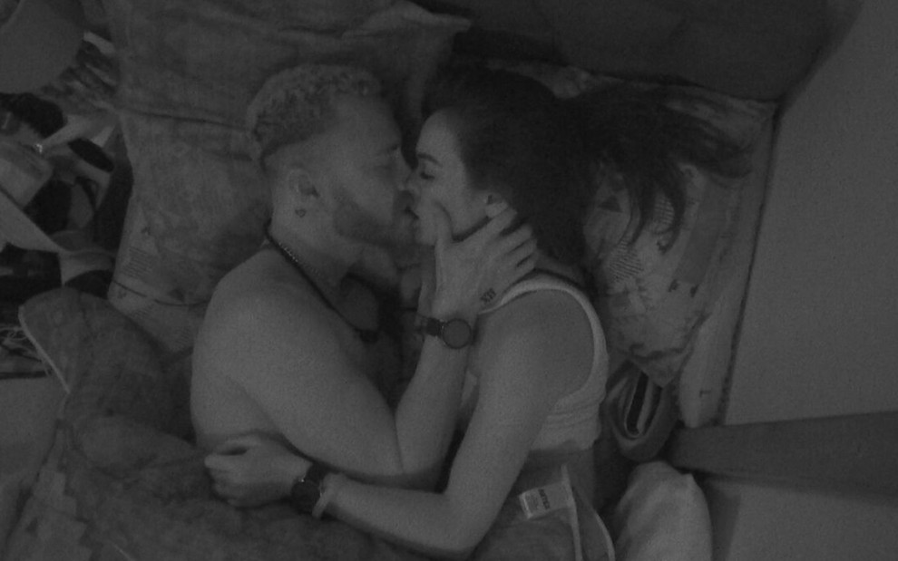 Fred e Larissa estão deitados e se beijando com as luzes apagadas no quarto