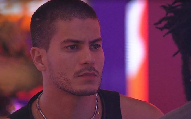 Arthur Aguiar olha para o lado e veste regata preta