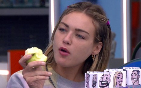Bárbara come uma maçã e olha para o lado
