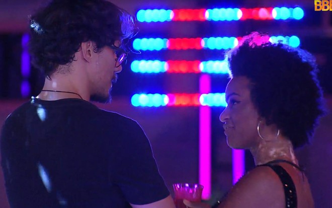 Eliezer veste camiseta preta e olha para Naty; Naty veste top preto e olha para Eliezer
