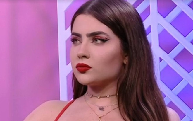 Jade veste top vermelho, usa batom vermelho e está com o cabelo solto