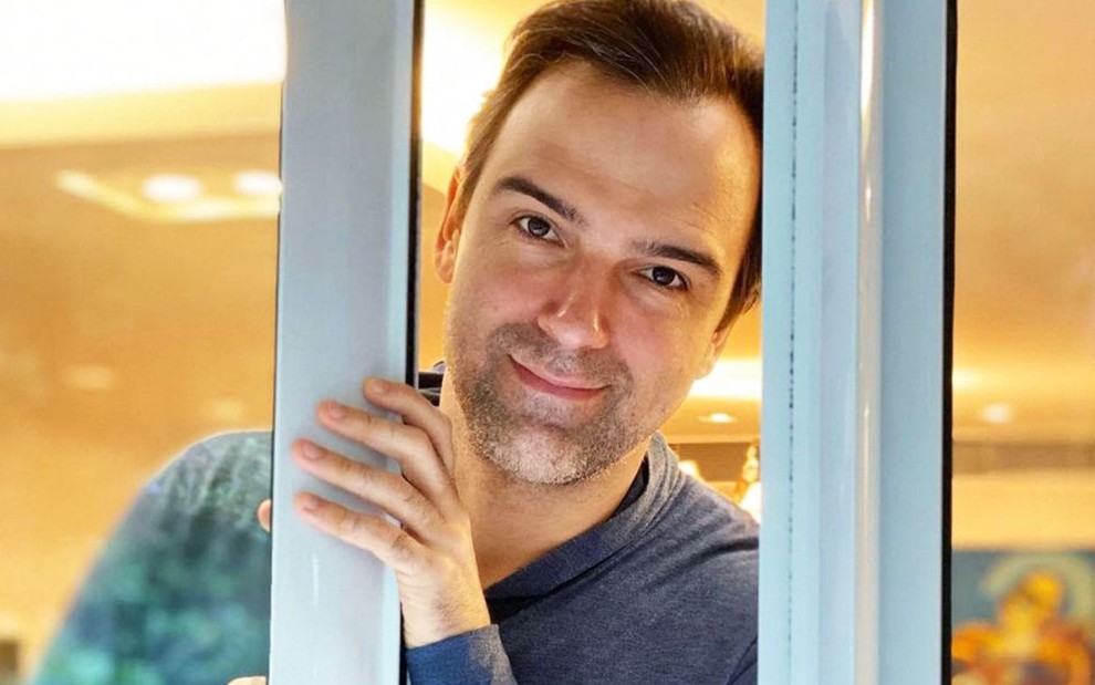 Tadeu Schmidt segura uma porta aberta enquanto sorri para a câmera em foto no Instagram