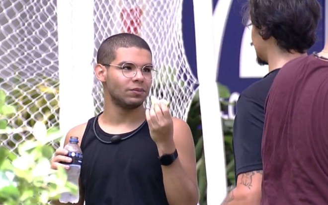 Imagem de Vinicius Fernandes (à esq.) e Eliezer Netto (de costas) na área externa do BBB 22