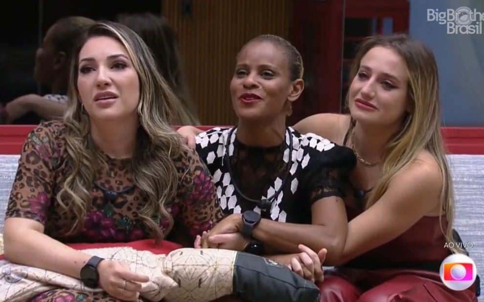 Amanda Meirelles, Aline Wirley e Bruna Griphao estão sentadas no sofá da sala do BBB 23