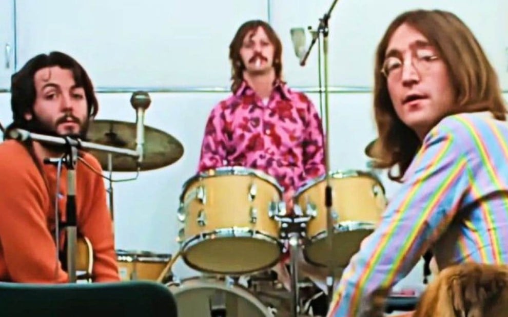 Paul McCartney, Ringo Starr e John Lennon em estúdio, em frente a bateria, olham para a câmera durante gravações que deram origem a The Beatles - Get Back