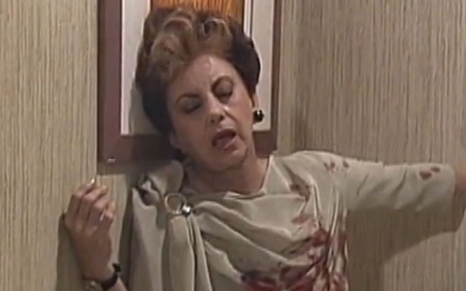 Beatriz Segall está apoiada em parede após levar tiro em cena como Odete Roitman na novela Vale Tudo