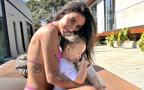 De biquíni rosa, Bianca Andrade abraça o filho, Cris, na área externa da sua casa