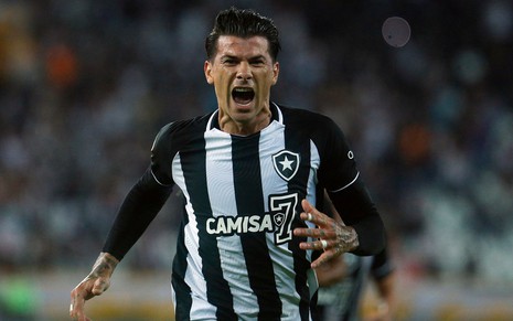 Jogador Cuesta, do Botafogo, grita ao comemorar gol e veste uniforme listrado em preto e branco