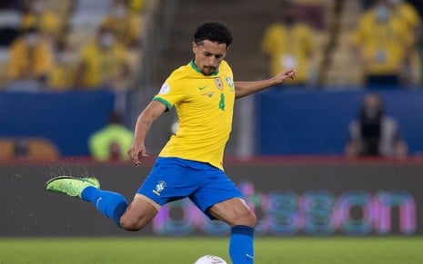 O zagueiro Marquinhos com a camisa amarela e verde do Brasil; ele está fazendo movimento para chutar a bola