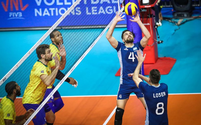 Jogadores do Brasil contra a Argentina na Liga das Nações de vôlei. O Brasil vê a seleção argentina levantar a bola para um ataque.