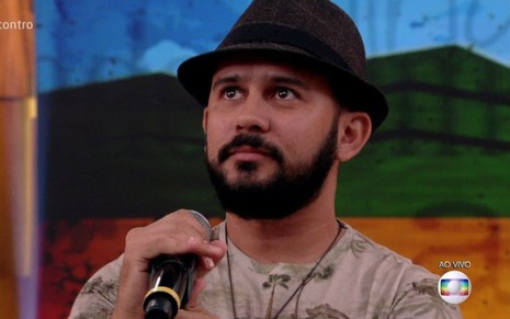 O poeta Bráulio Bessa durante participação no Encontro com microfone na mão, chapéu, olha para cima