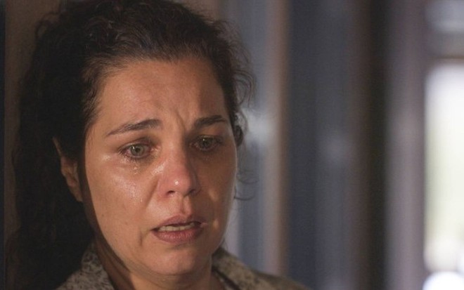 A atriz Isabel Teixeira como Maria Bruaca em Pantanal; ela está olhando para baixo com cara de espanto e tristeza