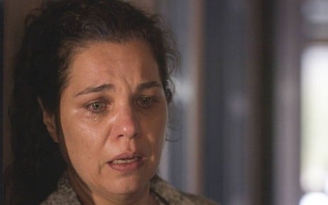A atriz Isabel Teixeira como Maria Bruaca em Pantanal; ela está olhando para baixo com cara de espanto e tristeza