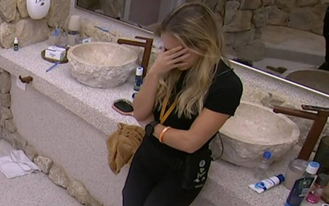 Foto mostra Bruna chorando encostada na pia do banheiro