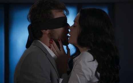 Com venda nos olhos, Rafael (Bruno Ferrari) está prestes a beijar Kyra/Cleyde (Vitória Strada) em Salve-se Quem Puder