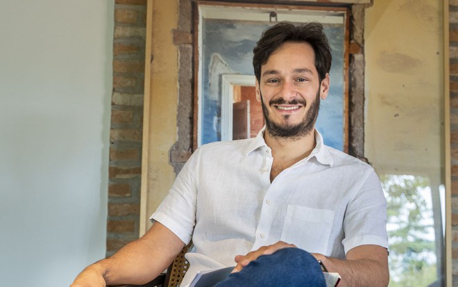 Retrato do autor de Pantanal, Bruno Luperi, que está sentado em uma cadeira