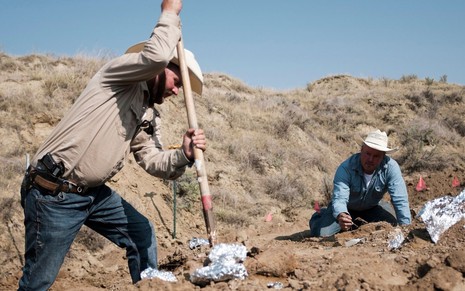 Imagem de Aaron Bolan e Jake Harris escavando uma propriedade de terra na série Caçadores de Dinossauros