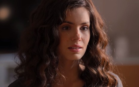 Camila Queiroz está com os cabelos cacheados e expressão pensativa na série De Volta aos 15