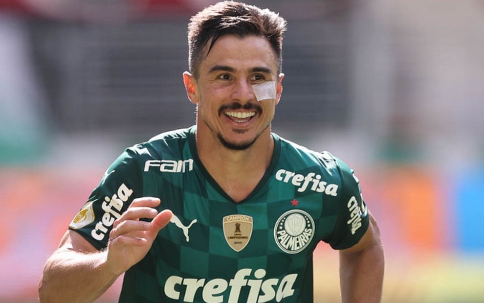 William, do Palmeiras, com a camisa verde do clube, comemorando um gol. Ele tem um machucado e um curativo abaixo do olho esquerdo.