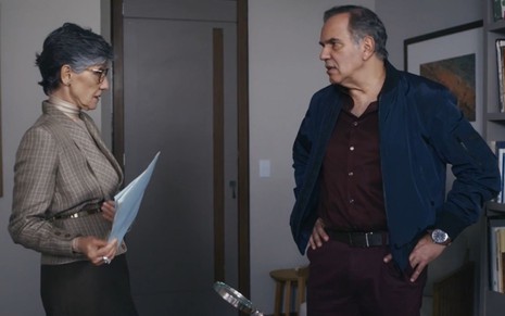 Cidália (Cassia Kis) e Guerra (Humberto Martins) estão em pé frente a frente em cena da novela Travessia
