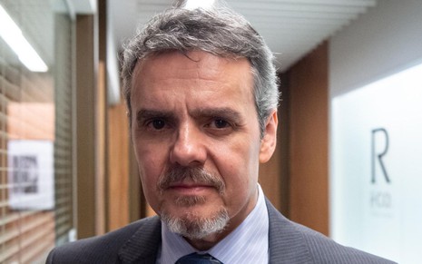 Cássio Gabus Mendes está com expressão séria e usa terno e gravata