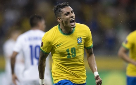 O jogador de futebol Raphinha grita vestindo camisa da Seleção Brasileira no jogo Brasil x Paraguai pelas Eliminatórias da Copa do Mundo na Globo