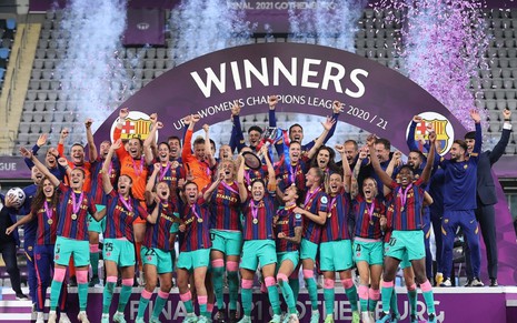 Jogadoras do Barcelona, com uniforme grená do clube e levantando as mãos para cima de alegria, erguendo o troféu da Uefa Women's Champions League da temporada 2020/2021
