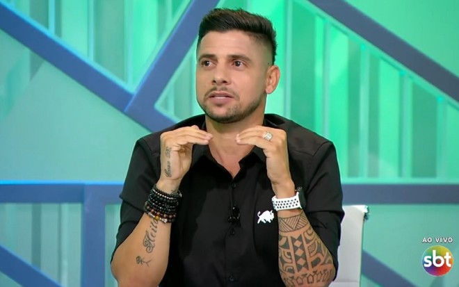 Ex-jogador Cicinho com uma camisa preta e comentando no programa Arena SBT, exibido nas noites de segunda