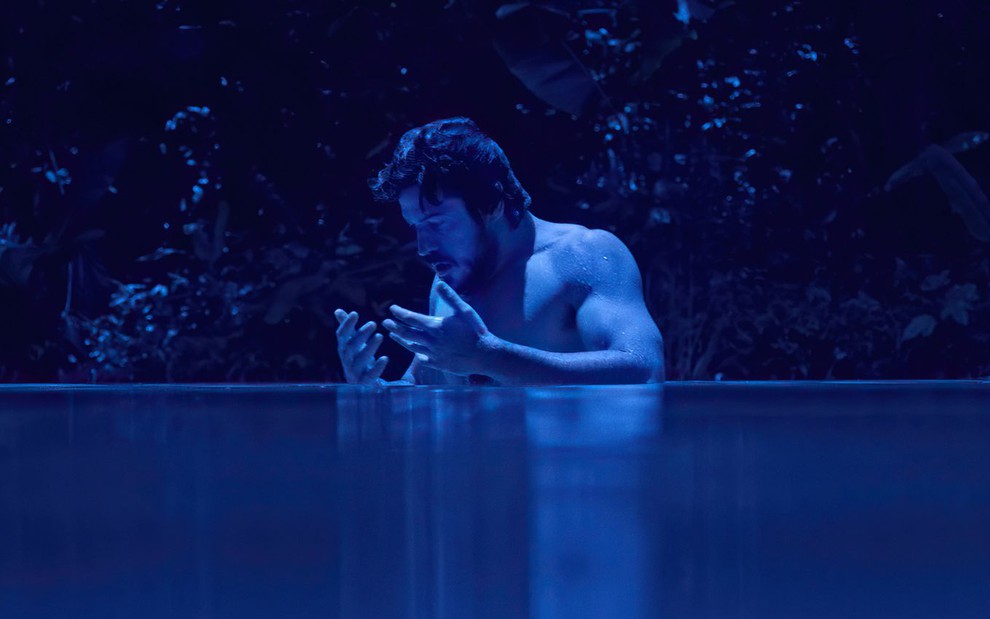 Marco Pigossi dentro de um rio em cena da segunda temporada da série Cidade Invisível