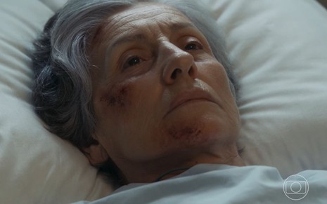 Cassia Kis está deitada em cana de hospital e expressa tristeza em cena como Cidália na novela Travessia