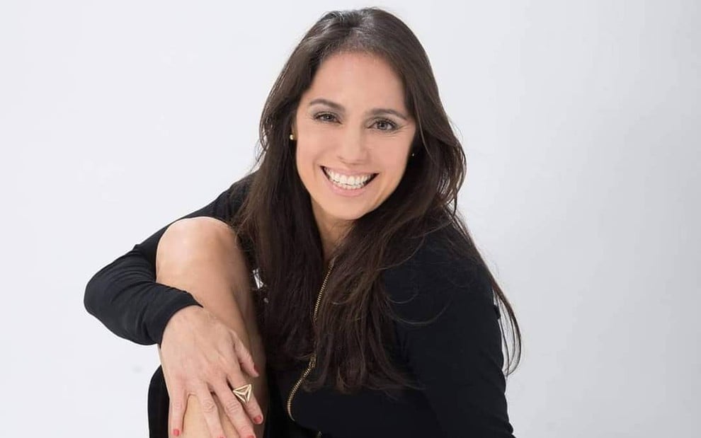 A atriz Claudia Mauro, com vestido preto, sorridente posando para foto