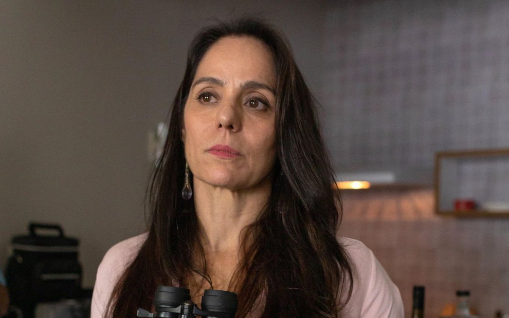 A atriz Claudia Mauro posa séria em cenário da novela Travessia caracterizada como a bandida Pilar