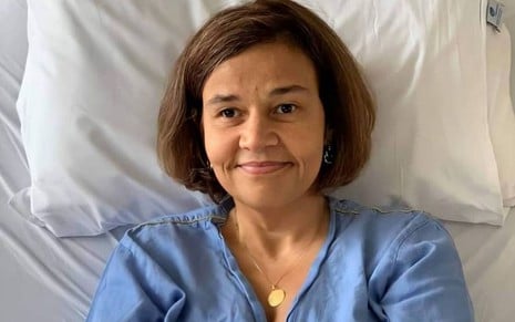 Claudia Rodrigues na cama de hospital com camisola azul