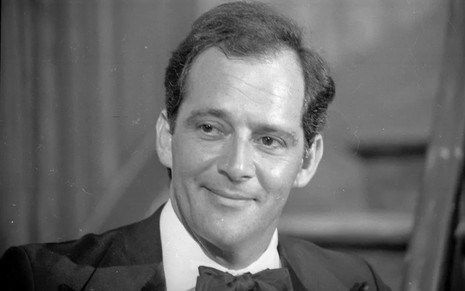 O ator Claudio Marzo com leve sorriso de boca fechada, de terno, gravata borboleta, em foto em preto e branco