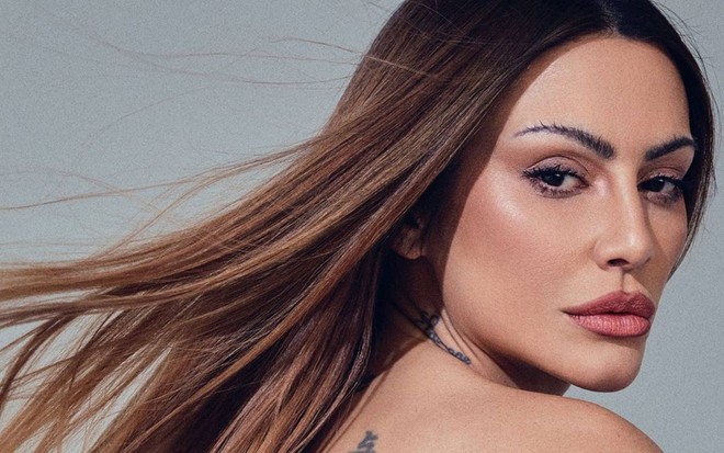 Cleo olha para o lado, está com o cabelo voando; a câmera está focada no rosto dela