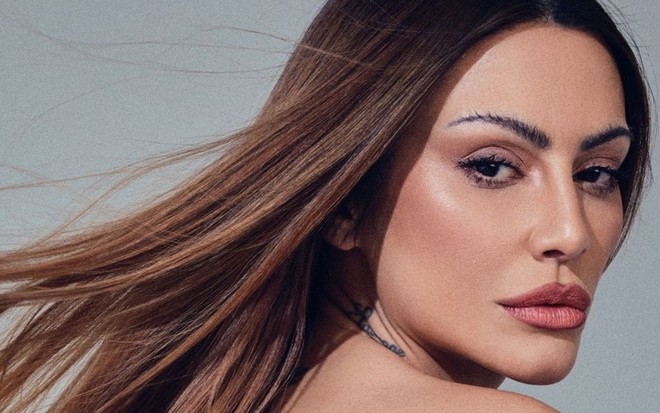 Cleo está com o cabelo solto e maquiada
