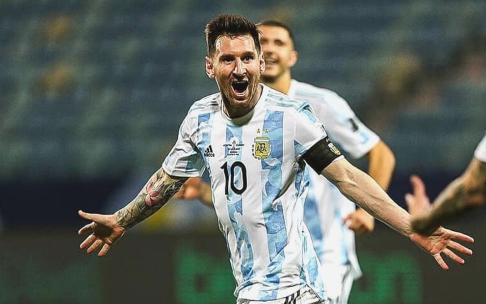 De braços abertos, Lionel Messi para comemorar gol marcado pela Argentina; ele está com o uniforme da seleção