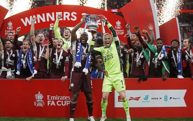 Jogadores do Leicester usam uma camisa azul e levantam o troféu da Copa da Inglaterra da temporada 2020/2021, no estádio Wembley, em Londres