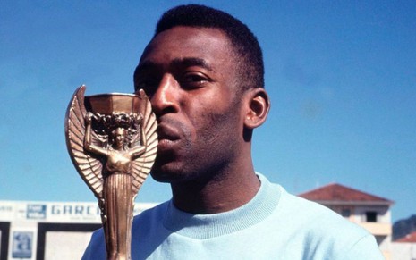 O ex-jogador Pelé, da Seleção Brasileira, segura e beija a taça Jules Rimet e veste blusa azul