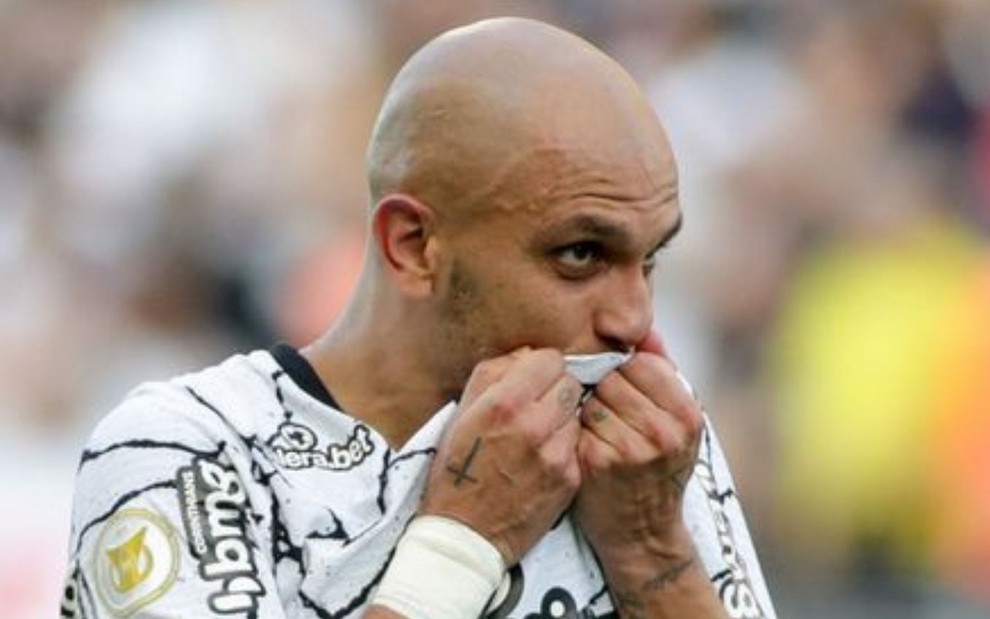 Jogador Fábio Santos, do Corinthians, beijando escudo da camisa branca com detalhes preto, durante jogo
