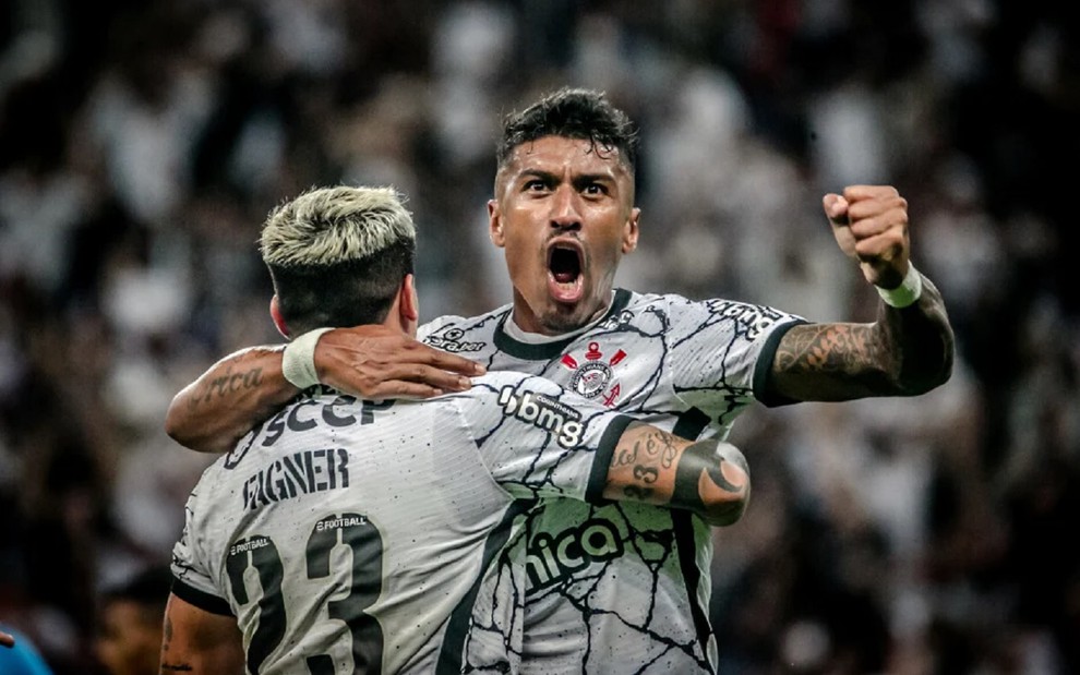 Com a camisa branca do Corinthians, Paulinho é abraçado por Fagner e vibra após gol