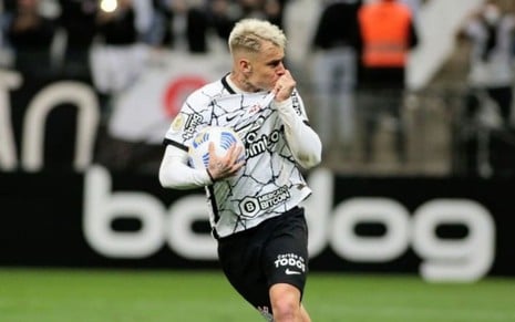 Jogador Róger Guedes, do Corinthians, vestindo uniforme branco e preto, comemorando gol feito em partida