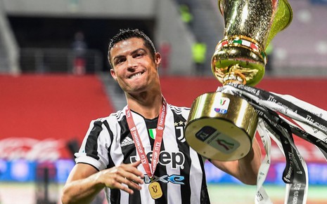 Cristiano Ronaldo com a camisa listrada em branco e preto da Juventus, sorrindo e levantando o troféu dourado da Copa da Itália
